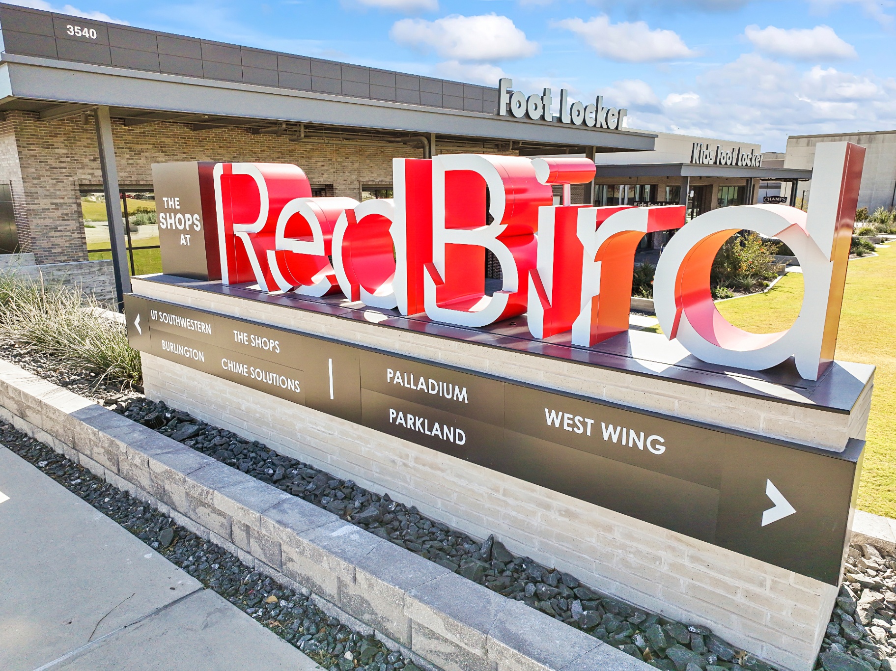 The Shops at RedBird monument sign with Foot Locker and Kids Foot Locker storefronts